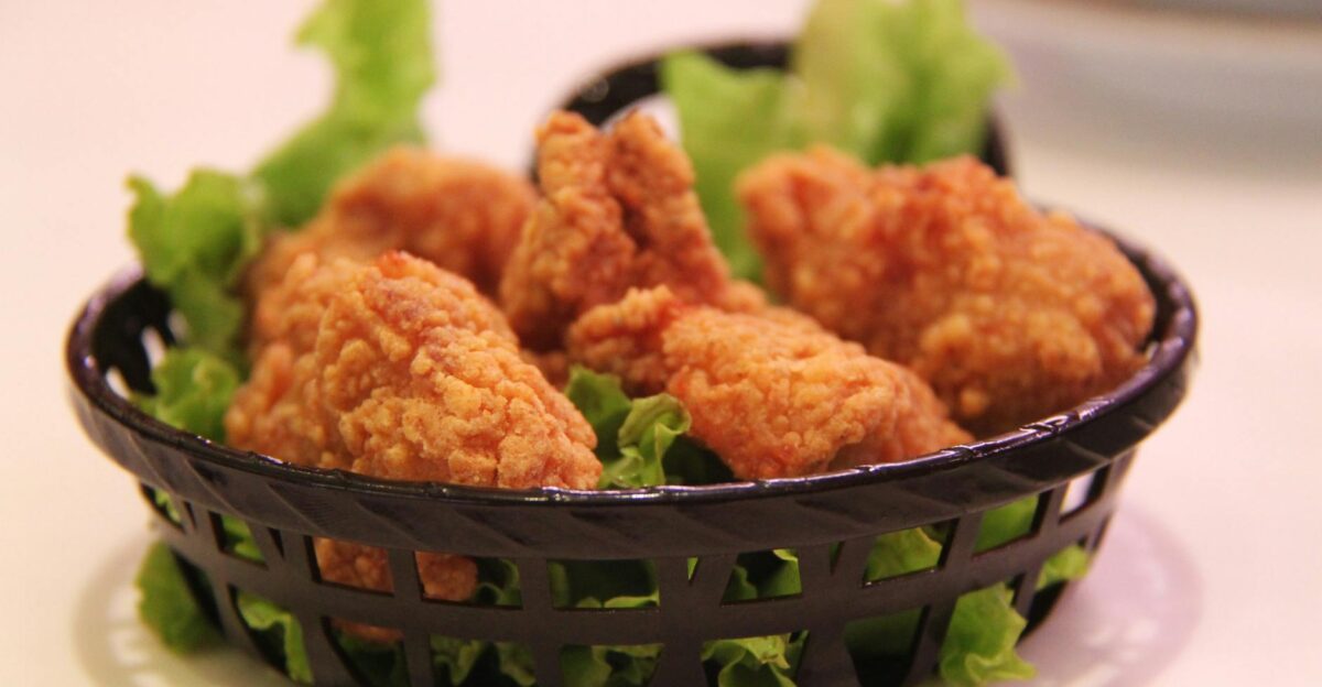 Close-up of crispy fried chicken served in a black basket with fresh lettuce highlighting food texture