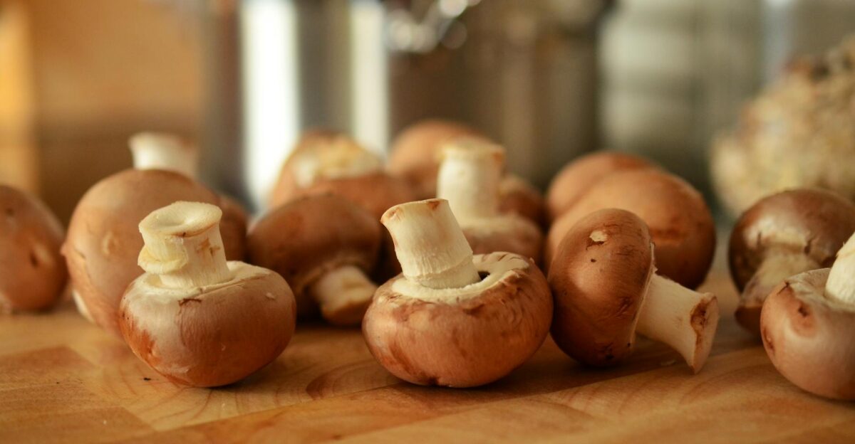 Close-up of fresh brown mushrooms on a wooden cutting board in a kitchen setting