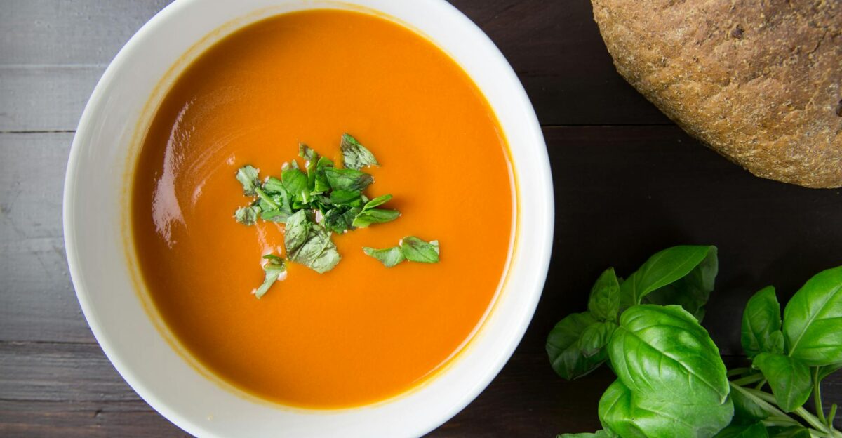 Delicious homemade tomato soup served with basil leaves and rustic bread