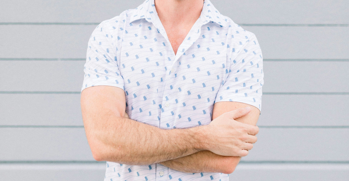 a man standing with his arms crossed in front of a wall